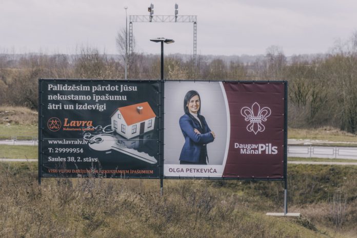 Баннер с рекламой партии Daugavpils — mana pils. Он двухсторонний. С одной стороны Ольга Петкевич, а с другой — Михаил Лавренов. 17 декабря 2024 года. Фото: Евгений Ратков