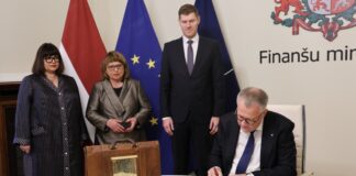 Министр финансов Арвилс Ашераденс передаёт портфель с законопроектом государственного бюджета на 2026 год представителям Сейма. 15 октября 2025 года. Фото: Finanšu ministrija / flickr