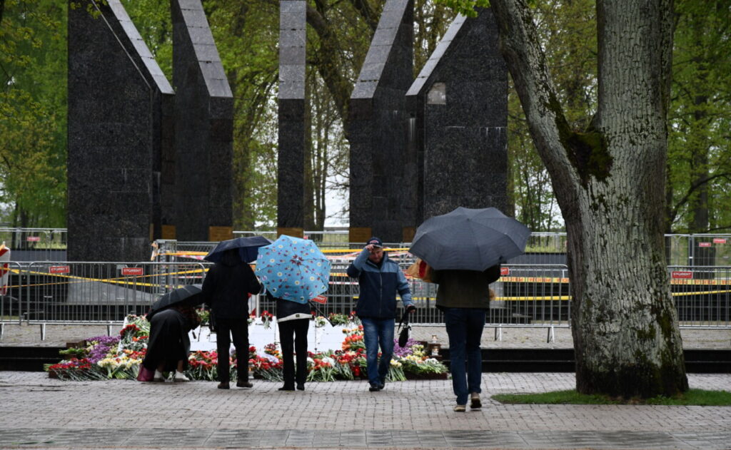Жители Даугавпилса возлагают цветы к мемориалу в Парке Дубровина. Сам мемориал по-прежнему ограждён, а по территории парка за порядком наблюдало несколько экипажей Государственной полиции. 9 мая 2026 года. Фото: Ивар Сойканс / LETA