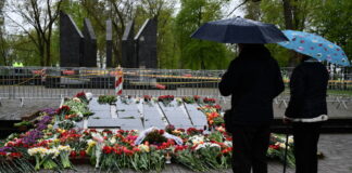 Жители Даугавпилса возлагают цветы к мемориалу в Парке Дубровина. Сам мемориал по-прежнему ограждён, а по территории парка за порядком наблюдало несколько экипажей Государственной полиции. 9 мая 2026 года. Фото: Ивар Сойканс / LETA