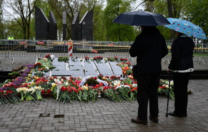Жители Даугавпилса возлагают цветы к мемориалу в Парке Дубровина. Сам мемориал по-прежнему ограждён, а по территории парка за порядком наблюдало несколько экипажей Государственной полиции. 9 мая 2026 года. Фото: Ивар Сойканс / LETA