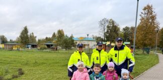 Сотрудники госполиции и маленькие пассажиры, получившие в подарок плюшевых котов Рудисов во время рейда в Крауе Аугшдаугавского края. 6 октября 2026 года. Фото: Анна Кусиня