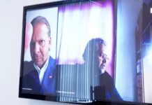 Обвиняемый по уголовному делу депутат Рижской думы, лидер партии «Стабильности!» и бывший депутат Сейма Алексей Росликов (на экране слева) во время судебного заседания в Рижском городском суде по уголовному делу о разжигании национальной и этнической ненависти. Фото: Иева Лейниша / LETA