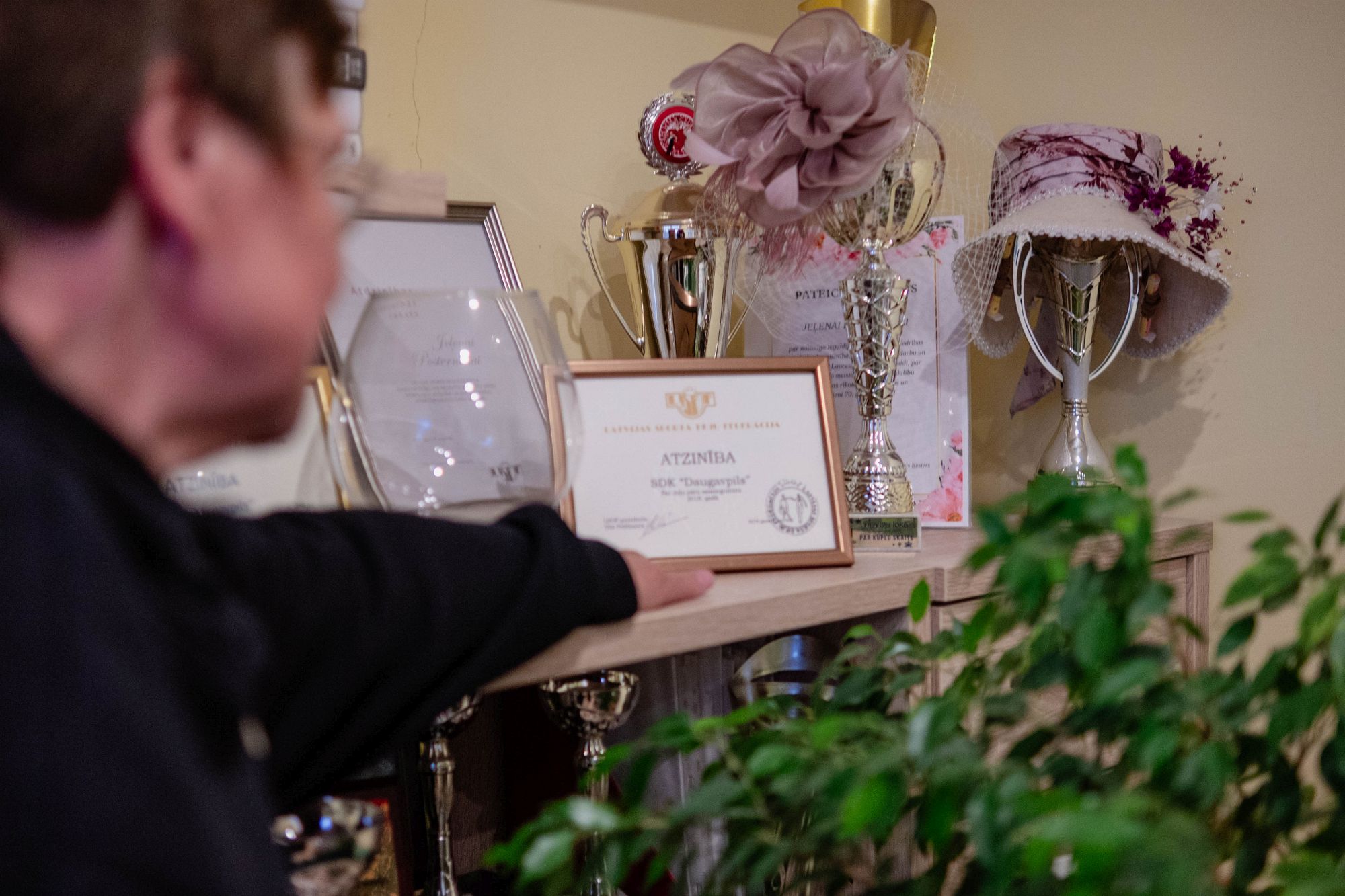 Елена показывает полку с кубками, грамотами и танцевальными аксессуарами.