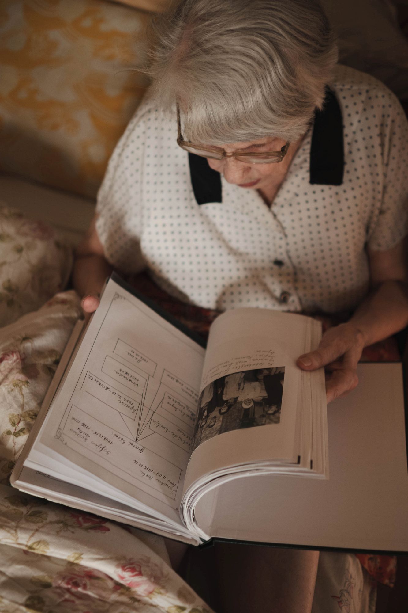 Вероника рассматривает открытую книгу или альбом с фотографиями и записями.